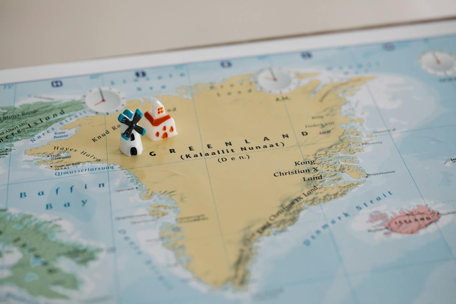 Toy houses on a detailed map of Greenland, highlighting geographic features. Ideal for travel concepts.