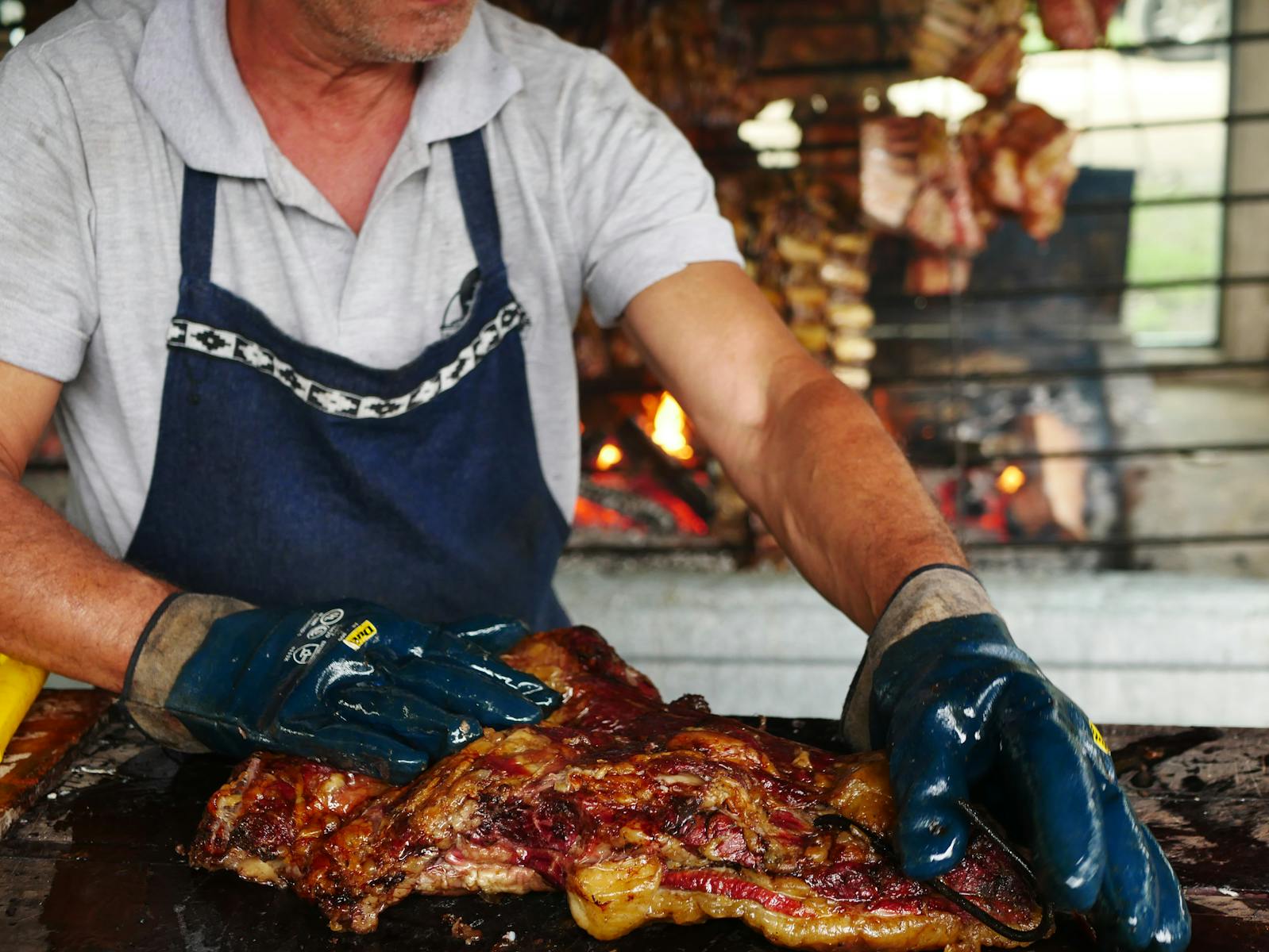 Traditional Argentine asado grilling with fire in Uribelarrea, showing detailed meat preparation.